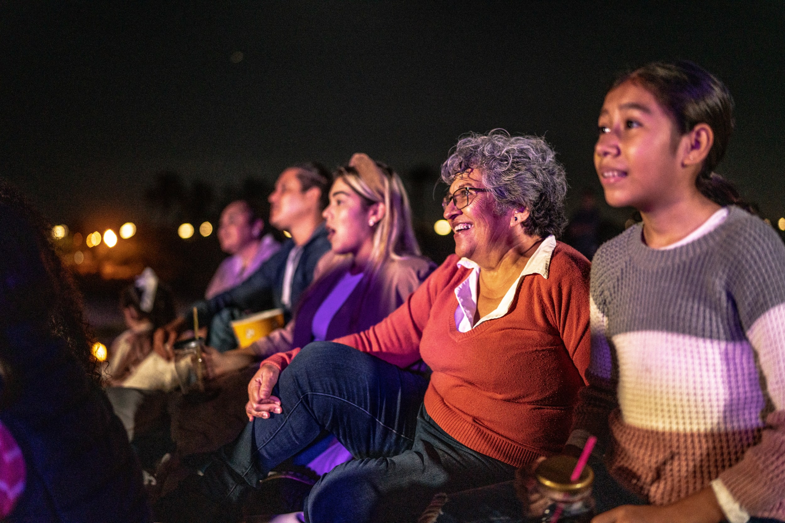 Family sit together watching an outdoor performance at night