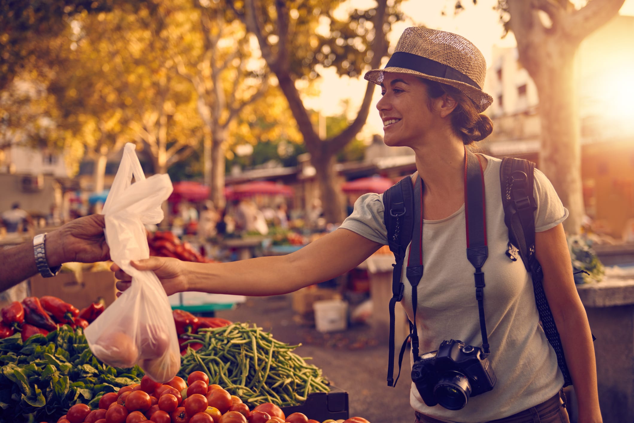 Woman buys fresh produce from outdoor market vendor in the sun