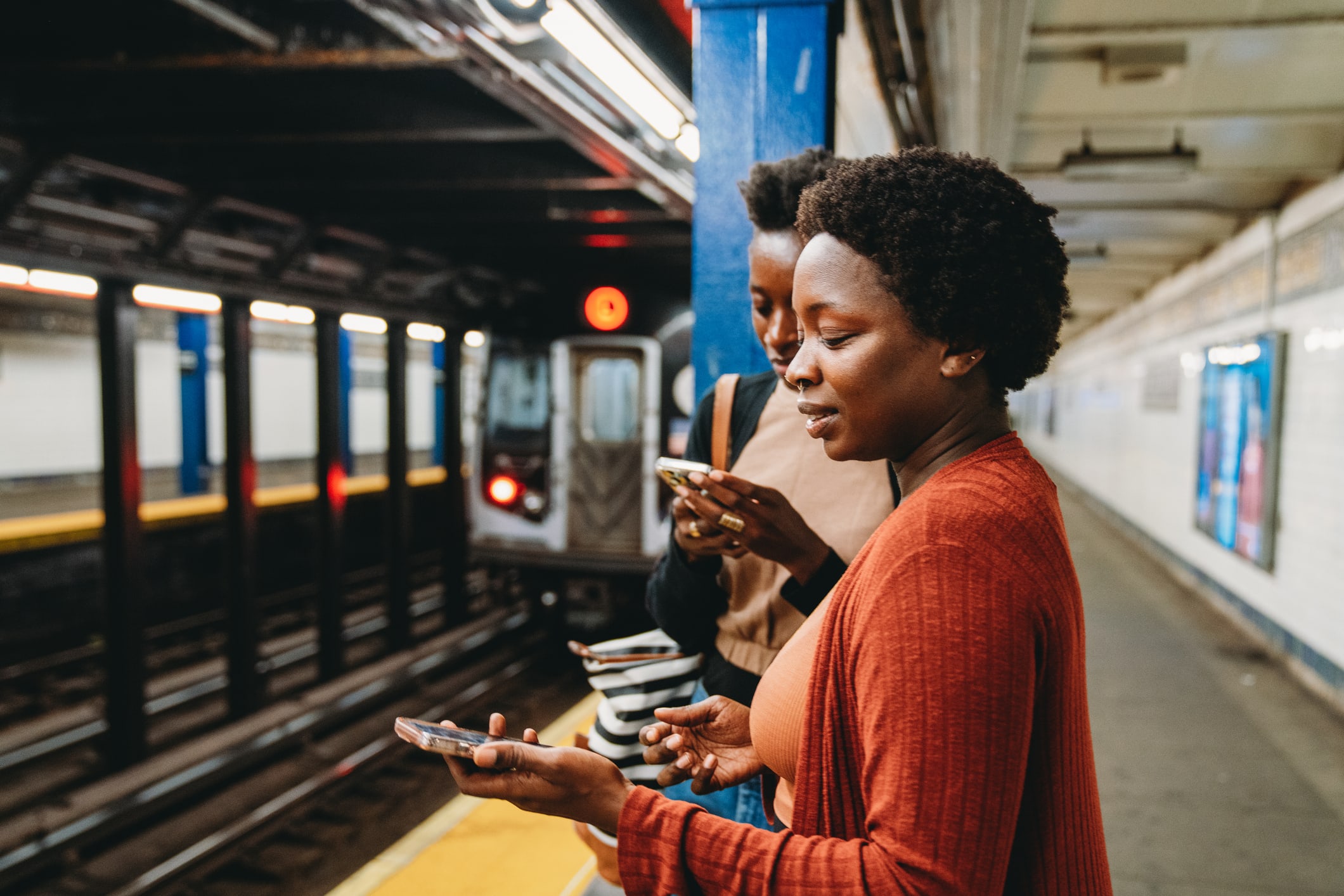 Woman waits for subway while looking at her phone 