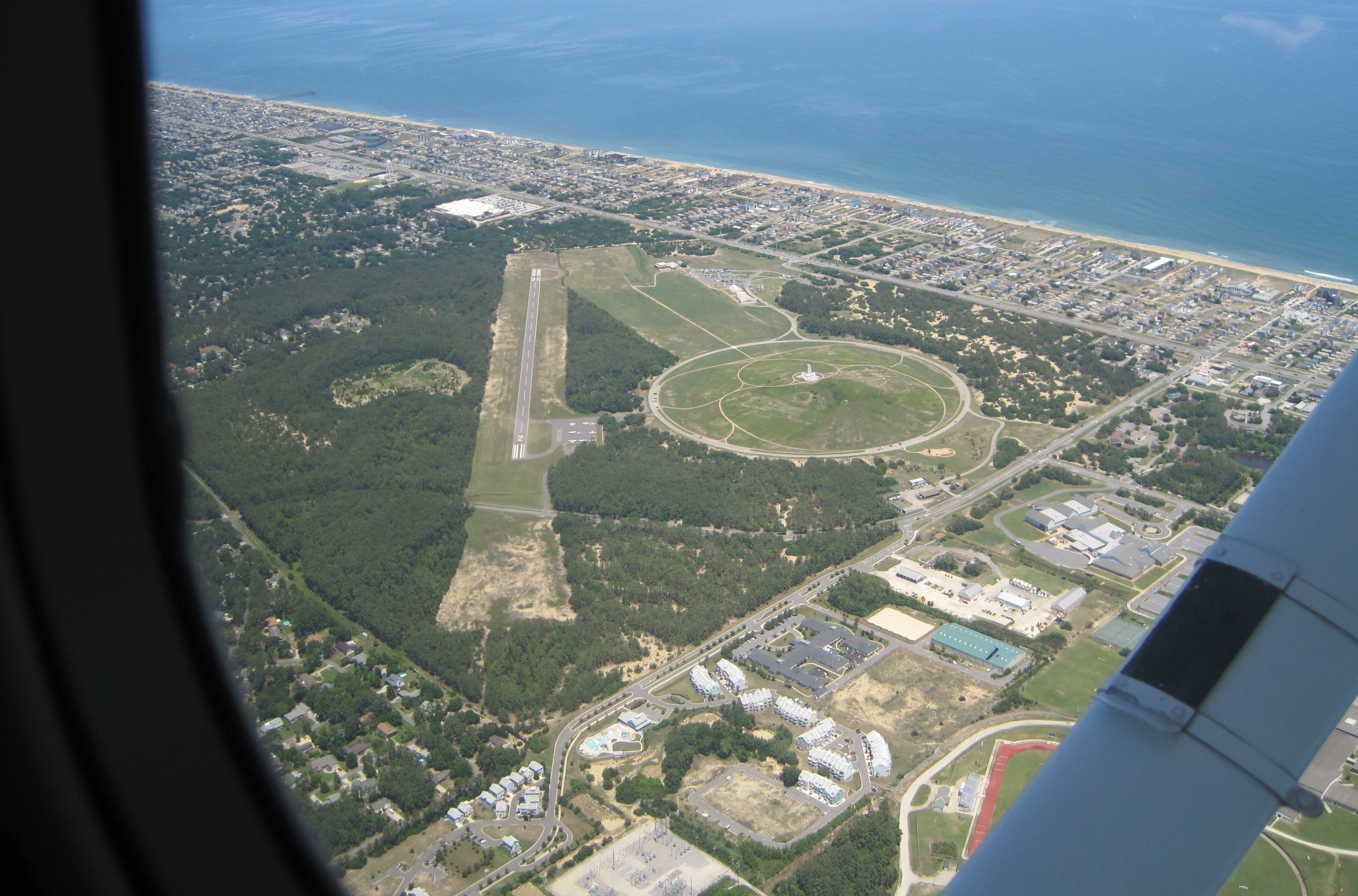 Aerial view through a Cessna window of the Wright Brothers Memorial, runway, and coastline