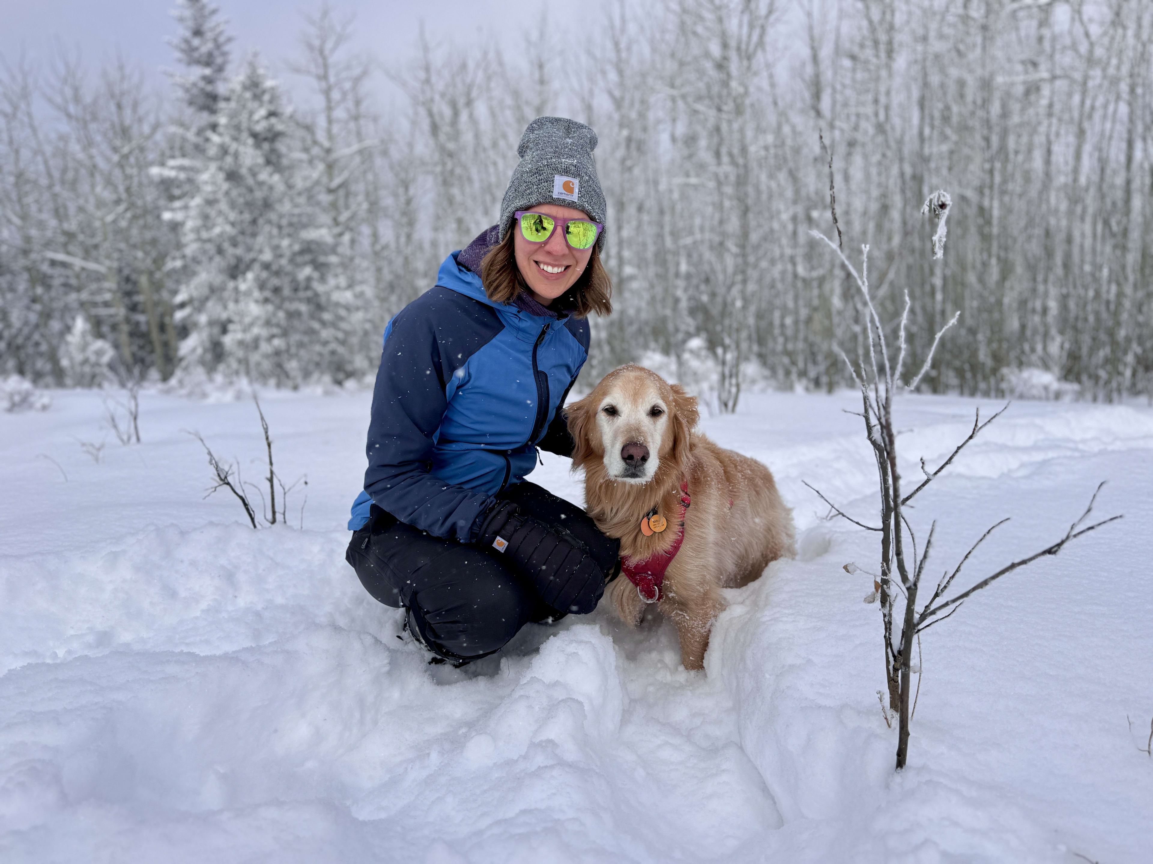 Bricelyn kneeling next to Milton in deep snow while it snows around them