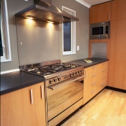 Kitchen with wooden cabinetry and black benchtop, stainless cabinetry, countertop, cuisine classique, floor, flooring, hardwood, interior design, kitchen, room, wood, wood flooring, orange