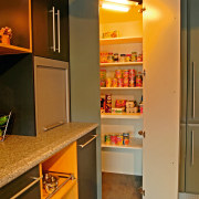 Showroom kitchen with grey benchtop, dark grey and cabinetry, closet, countertop, furniture, interior design, kitchen, room, shelf, shelving, brown, orange