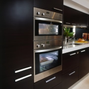 Kitchen with dark timber veneer cabinetry with stainless countertop, home appliance, kitchen, kitchen appliance, kitchen stove, major appliance, oven, black