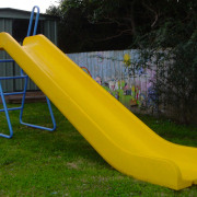 Bright yellow play slide with blue ladder. - chute, leisure, outdoor furniture, outdoor play equipment, playground slide, yellow, black, brown