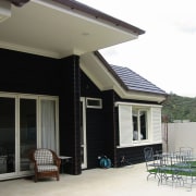 View of the back patio - View of facade, home, house, porch, property, real estate, residential area, roof, siding, window, white, black, gray