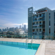 Rooftop swimming pool with timber decking and another apartment, architecture, building, city, condominium, corporate headquarters, daytime, estate, hotel, metropolitan area, mixed use, property, real estate, residential area, sea, sky, swimming pool, tower block, water, teal