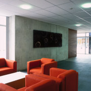 Lobby of building with concrete wall, floor tiles, architecture, ceiling, floor, furniture, interior design, lobby, table, wall, gray