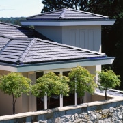 Exterior view of apartment showing concrete roof tiles, cottage, facade, home, house, outdoor structure, plant, real estate, residential area, roof, tree, window, black