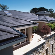 Balcony area of apartment complex featuring grey concrete daylighting, house, outdoor structure, real estate, residential area, roof, solar panel, solar power, black