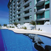 Curved edge pool with rock and garden features apartment, architecture, building, condominium, estate, hotel, property, real estate, resort, sky, swimming pool, blue