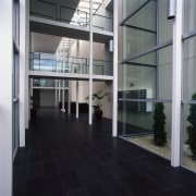 Lobby area of apartment complex featuring basalt paving, architecture, building, condominium, daylighting, floor, flooring, glass, interior design, lobby, real estate, window, black, gray