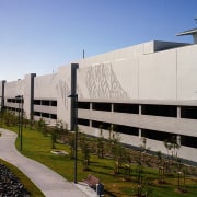 Exterior view along concrete wall of complex with architecture, building, corporate headquarters, daytime, facade, headquarters, house, neighbourhood, residential area, sky, structure, gray, teal