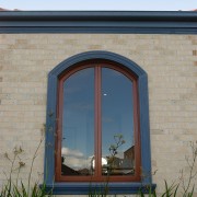 Exterior of brick clad house featuring timber arched arch, architecture, facade, home, sky, wall, window, teal, gray