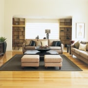 Large living area with timber floors, large rug, bed frame, coffee table, couch, floor, flooring, furniture, hardwood, interior design, laminate flooring, living room, room, table, wall, wood, wood flooring, white