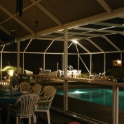Eating area and pool area enclosed in glass lighting, night, black