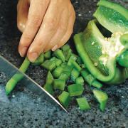 Closeup of granite benchtop with someone chopping vegetables. green, local food, vegetable, black, green