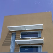 Exterior of house showing windows and louvres. - architecture, building, commercial building, condominium, daylighting, daytime, elevation, facade, home, house, line, property, real estate, residential area, sky, window, blue