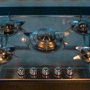 Closeup of five-burner gas hob with stainless steel black, teal