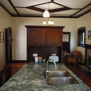 Kitchen with dark coloured cabinetry and furniture, light ceiling, floor, flooring, interior design, living room, real estate, room, wood, black, gray