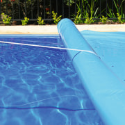 Swimming pool with blue cover being rolled up. azure, blue, leisure, swimming pool, water, teal, blue