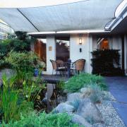 View of the patio area, concrete slab blocks backyard, cottage, courtyard, garden, home, house, landscaping, outdoor structure, patio, plant, property, real estate, roof, yard, white