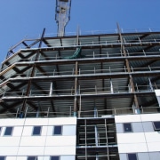 Exterior view of apartment building under construction. architecture, building, commercial building, condominium, construction, corporate headquarters, daytime, facade, headquarters, metropolis, metropolitan area, mixed use, residential area, scaffolding, sky, tower block, window, black, blue