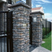 Closeup of schist stone pillars and black iron brickwork, fence, outdoor structure, stone wall, structure, walkway, wall, black, gray