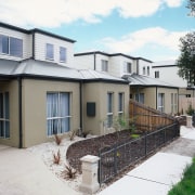 Exterior of townhouses with tan coloured cladding on cottage, elevation, estate, facade, home, house, neighbourhood, property, real estate, residential area, siding, suburb, window, yard, white