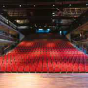 Large theatre arena with red seats and timber arena, audience, auditorium, concert hall, performing arts center, sport venue, stage, structure, theatre, black, red