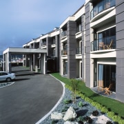 Exterior view of hotel entranceway with balconies at apartment, architecture, building, condominium, corporate headquarters, elevation, estate, facade, home, house, mixed use, neighbourhood, property, real estate, residential area, window, teal, gray, black