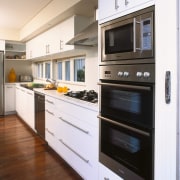 A view of a kitchen area, wooden flooring, cabinetry, countertop, home appliance, kitchen, kitchen appliance, kitchen stove, major appliance, microwave oven, oven, white, brown