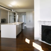 A view of a fireplace surrounded by marble, countertop, fireplace, floor, flooring, hardwood, hearth, home appliance, interior design, kitchen, laminate flooring, living room, real estate, room, wood, wood flooring, white, brown