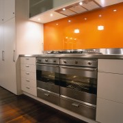 A view of a kitchen, wooden flooring, orange cabinetry, countertop, cuisine classique, home appliance, interior design, kitchen, kitchen stove, major appliance, room, under cabinet lighting, gray