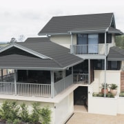 An exterior view of a house, grey tiled daylighting, elevation, facade, home, house, outdoor structure, porch, property, real estate, residential area, roof, siding, window, white, gray