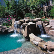 view of the pool area that includes a arecales, backyard, body of water, landscape, landscaping, leisure, pond, swimming pool, tree, water, water feature, water resources, watercourse, waterfall, gray, black