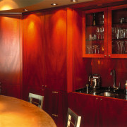 A view of a kitchen, wooden cabinetry and interior design, lighting, room, table, red