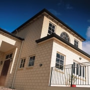 view of this house featuring  florentine limestone building, facade, home, house, property, real estate, residential area, roof, siding, sky, window, blue, brown