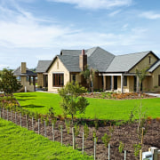 view of the house featuring plastered and lime cottage, estate, facade, farm, farmhouse, fence, field, grass, home, house, land lot, landscape, landscaping, lawn, outdoor structure, plantation, property, real estate, residential area, roof, rural area, sky, tree, yard, white