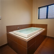 White bath with brown surround. - White bath bathroom, bathtub, daylighting, floor, interior design, jacuzzi, plumbing fixture, property, real estate, room, tile, brown