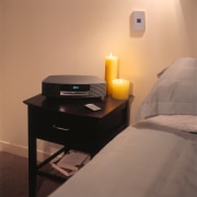 a bose wave music centre features in the bed, bed frame, bedroom, chest of drawers, floor, furniture, interior design, light fixture, lighting, nightstand, product design, room, suite, table, orange, brown
