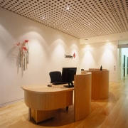 A view of the signage placed about the ceiling, desk, floor, flooring, furniture, interior design, lobby, office, product design, table, wood, wood flooring, orange, brown