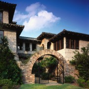 The archway is designed to look as if arch, building, cottage, estate, facade, hacienda, home, house, mansion, medieval architecture, property, real estate, sky, tree, villa, village, wall, blue