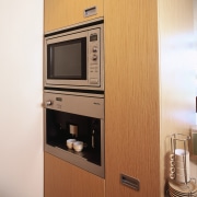 A view of a kitchen, wooden cabinetry and cabinetry, furniture, home appliance, kitchen, kitchen appliance, major appliance, microwave oven, orange, white, brown