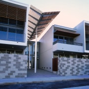 An exterior view of an entrance way with architecture, building, commercial building, condominium, corporate headquarters, daylighting, daytime, facade, headquarters, house, property, real estate, residential area, sky, window, blue, white