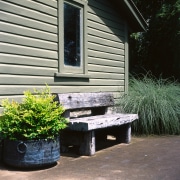 the rear wall of the garden shed is backyard, bench, furniture, siding, table, walkway, wall, window, yard, black, gray