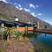 view of theis new house tucked beneath the alps, cottage, fjord, home, house, lake, landscape, mount scenery, mountain, mountain range, mountainous landforms, national park, nature, plant, real estate, reflection, reservoir, sky, tree, water, wilderness, blue