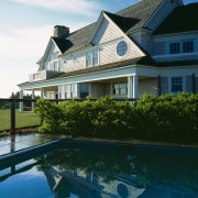 Exterior view of large house with weatherboard cladding, architecture, building, cottage, estate, home, house, mansion, property, real estate, reflection, residential area, roof, sky, swimming pool, villa, water, teal