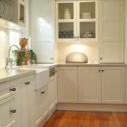 Kitchen with white cabinetry, metal handles, sunken sink, cabinetry, countertop, cuisine classique, floor, flooring, hardwood, home, home appliance, interior design, kitchen, laminate flooring, room, tile, wall, wood, wood flooring, wood stain, brown, orange