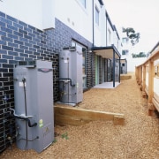 Rain water tanks next to grey brick building. architecture, facade, home, house, property, real estate, residential area, white